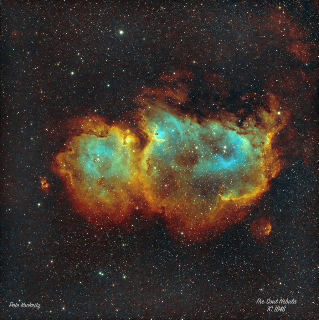 A reddish, orange and green nebula, shaped like a footprint.